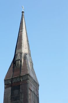 Curious black net shrouded Christian church steeple against blue sky