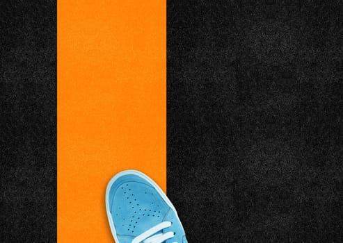 Blue sport shoe on orange line in street