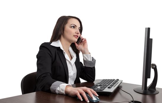 Image of a young brunette woman working on a computer and using a mobile phone , isolated against a white background.