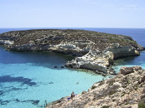 This is the magnificent island of rabbits, in Lampedusa. The water is crystal clear and the sand is white. The rocks are silhouetted against the blue sea and the sky is clear. The depths of this island are a paradise for divers because they are full of colorful fish. 
In this beach nesting turtles, who do travel miles to come to lay their eggs.  This area is protected reserves.