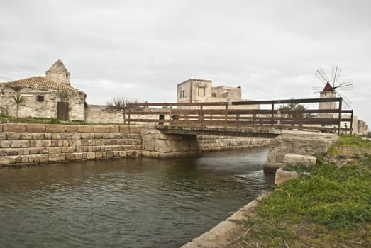 Old windmill on the salines near trapani with lake and bridge