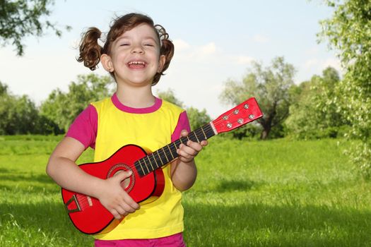 happy little girl play guitar in park
