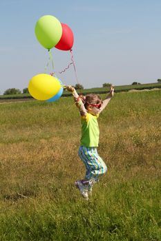 little girl running on field with balloons