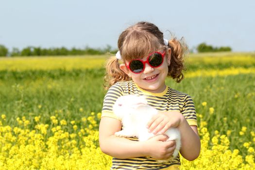little girl with bunny pet in yellow field