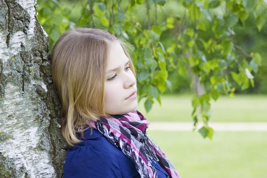 Portrait of young girl standing near birch tree in summer green park