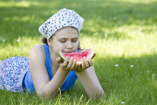 cute little girl eating watermelon on the grass