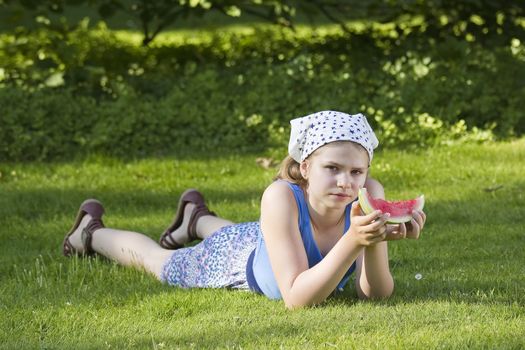 cute little girl eating watermelon on the grass