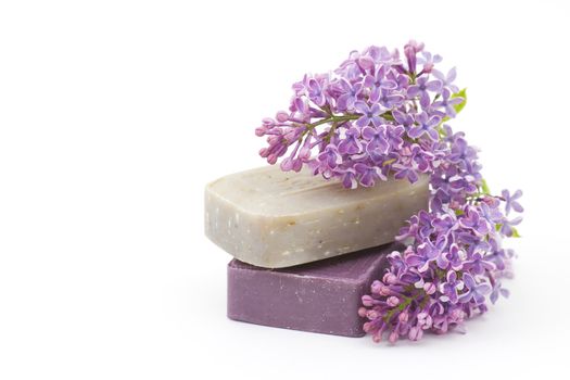 two bars of natural soap and lilac flowers isolated on white