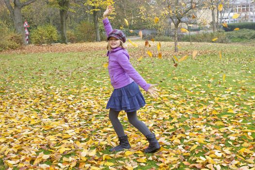 little girl plays with autumn leaves 