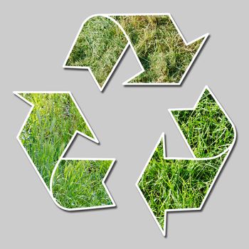 conceptual recycling sign with grass over gray background