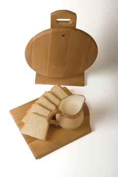 slices of bread and milk jug on a board on a white background