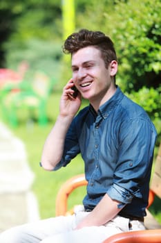Happy young man in park at telephone