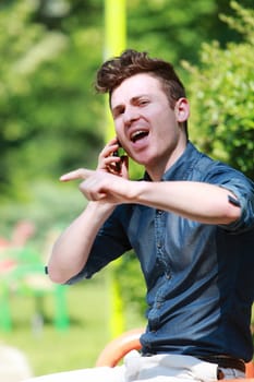 Young red hair man in the park talk on telephone
