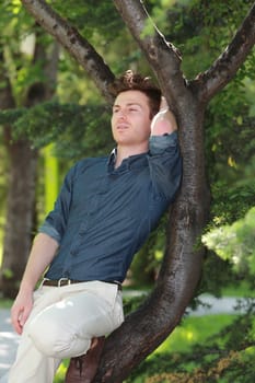 Portrait of handsome man relaxed on tree