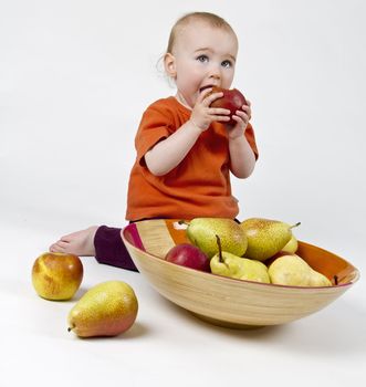 baby with apples and pears laying in bowl - studio shot with neutral background
