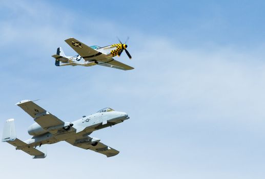 A P-51 mustang flying with an A-10. Both planes very well known for their time. image shot slightly below and in front of showing mostly their profile.