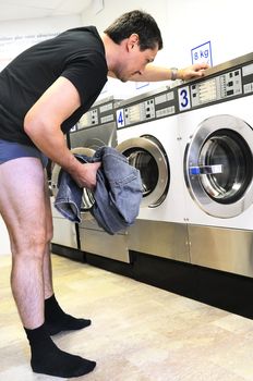 man is using washing machines in a public laundromat 