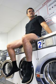 man is using washing machines in a public laundromat 