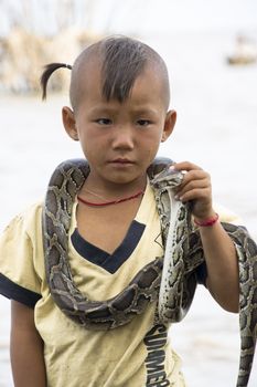 CAMBODIA – May 2012: Young Snake performer at Tonle Sap Lake in Cambodia in May 2012.  Living conditions in the area are difficult - Cambodia
