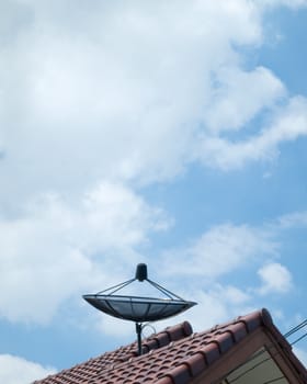 Black Satellite dish on red roof and bright sky