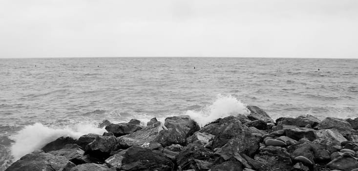 Raging sea breaking to the rocks, black and white