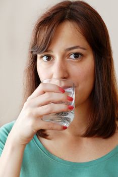 portrait of young caucasian brunette woman with glass in hand drinking water