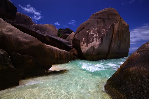 Clear ocean water washes in among weathered shore rocks worn smooth from years of waves