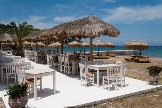 Empty tables and umbrelas in restaurant by the sea, Spetses island, Greece