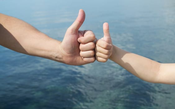 adult and children's hand gestures showing everything is fine in the background of the sea