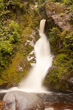 Forest waterfall cascading down rocky slope with silky appearance from long exposure