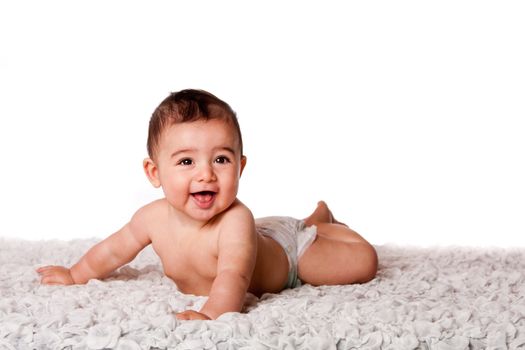 Cute happy smiling baby laying on belly on soft surface wearing diaper, isolated.