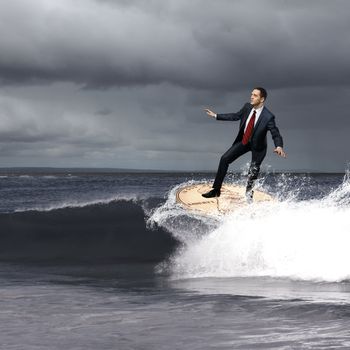 Image of young business person surfing on the waves of the ocean