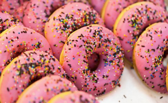 Sweet pink fresh donuts at shop counters