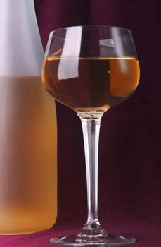 white wine in glass and bottle on a claret background