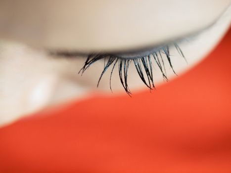Macro picture of a beautiful woman eyelashes from top on orange background