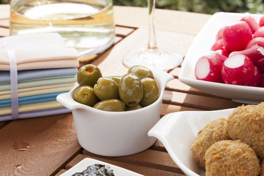 Green olives stuffed with red pimento in small white bowl.