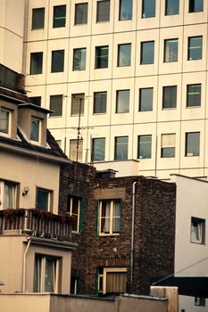 Rows of apartment windows towering above conventional homes with gables and decks