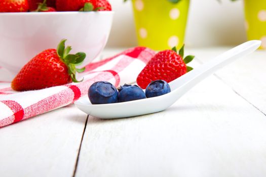 fresh blueberry in white porcelain spoon, wooden background