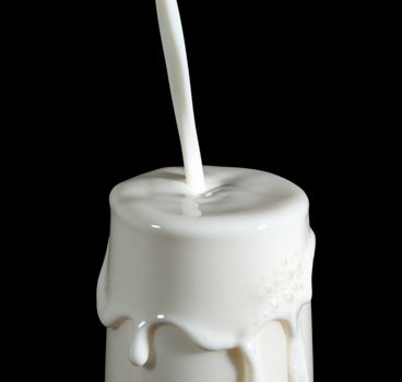 Pouring Milk in Glass, on black background