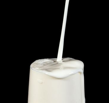 Pouring Milk in Glass, on black background
