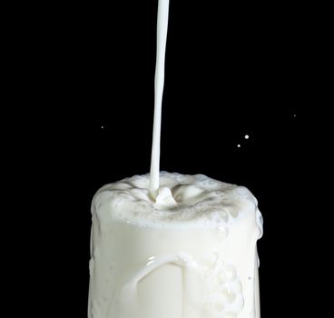 Pouring Milk in Glass, on black background