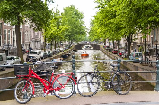 Detail of bicycles locked on top of bridge in Amsterdam, Holland, with traditional canal in the background.