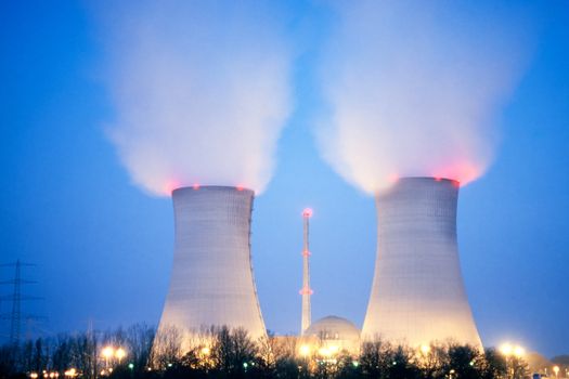 Nuclear power plant blowing huge clouds into dusky sky.