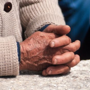 Folded hands of old working person waiting