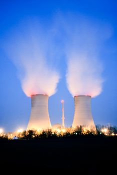 Nuclear power plant blowing huge clouds into dusky sky.