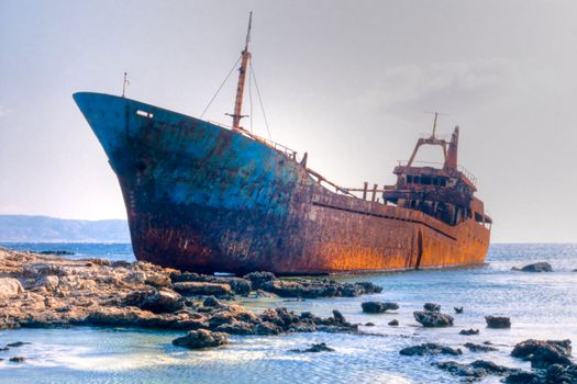 Abandoned broken ship-wreck beached on rocky sea shore.
