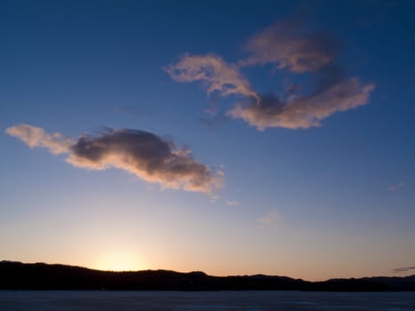 Sunset clouds over ice surface of frozen Lake Laberge,  Yukon Territory, Canada, in April