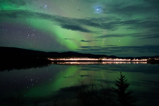 Night Sky Stars, clouds and Northern Lights over country road at lake shore, Yukon, Territory, Canada.