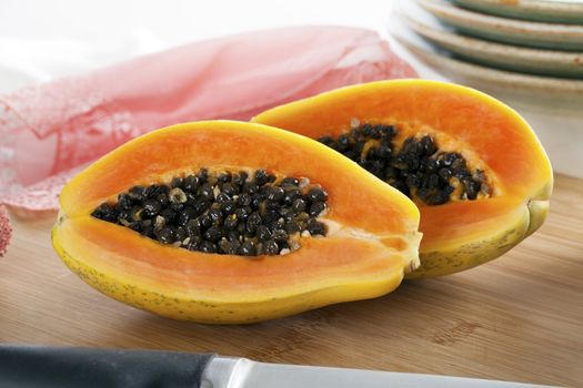 Papaya sliced in two sitting on cutting board