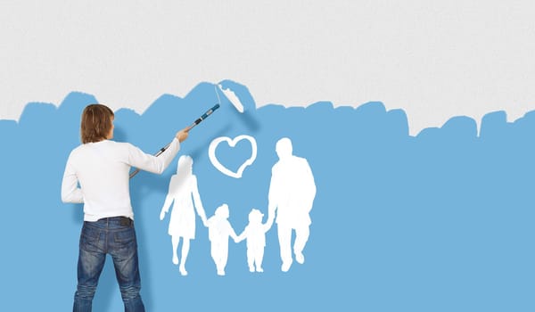 Young man with a paintbrush and family picture on the wall